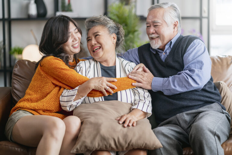 happiness asian family candid daughter hug grandparent mother farther senior elder cozy relax sofa couch surprise visiting living room hometogether hug cheerful asian family home